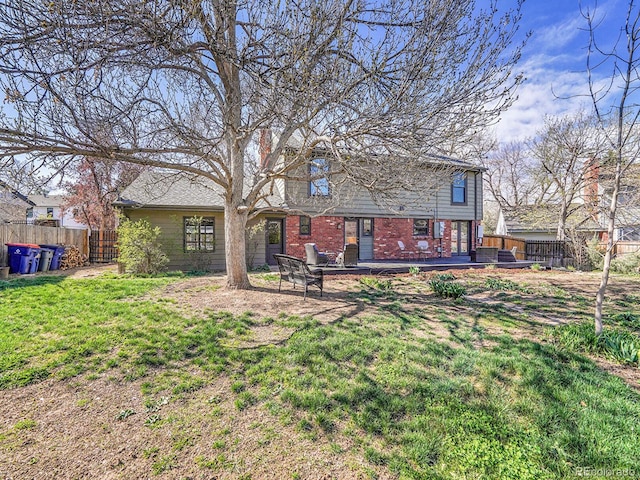 back of house with brick siding, fence, a yard, and a wooden deck