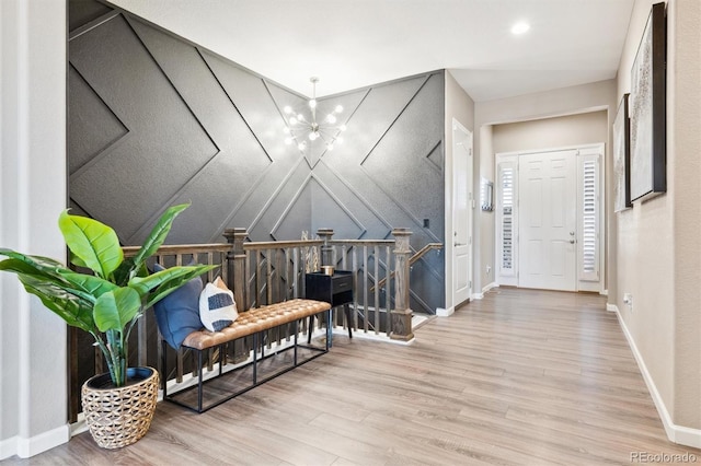 sitting room featuring baseboards, lofted ceiling, wood finished floors, an upstairs landing, and a chandelier