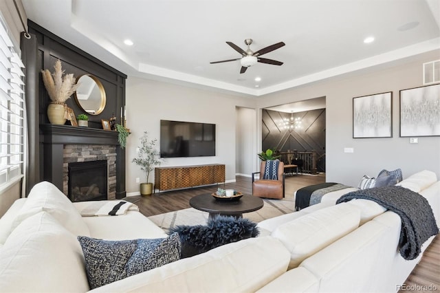 living area with a fireplace, a tray ceiling, wood finished floors, and recessed lighting