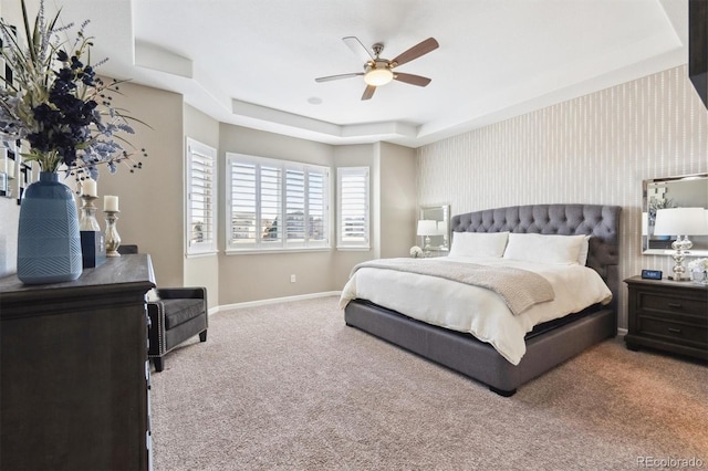 bedroom featuring carpet floors, wallpapered walls, baseboards, and a tray ceiling