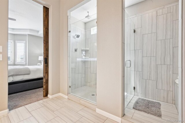 bathroom featuring connected bathroom, a shower stall, and baseboards