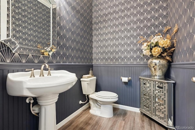 half bathroom with wainscoting, wood finished floors, and toilet