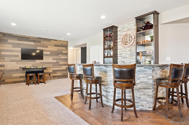 bar featuring recessed lighting, an accent wall, wood finished floors, visible vents, and a bar