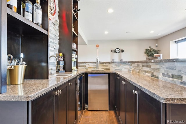 bar with tasteful backsplash, light wood-style floors, fridge, a sink, and recessed lighting