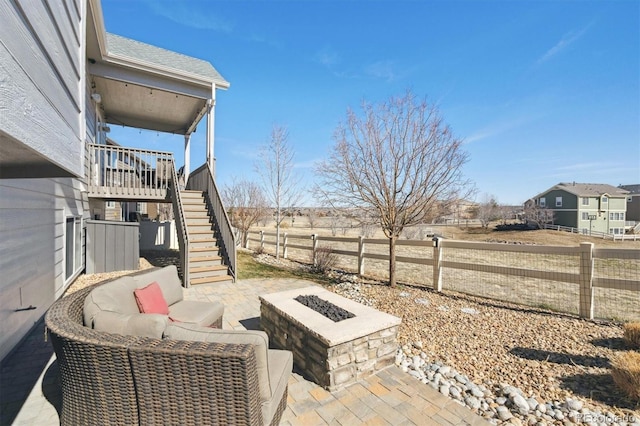 view of patio with an outdoor fire pit, fence, and stairs