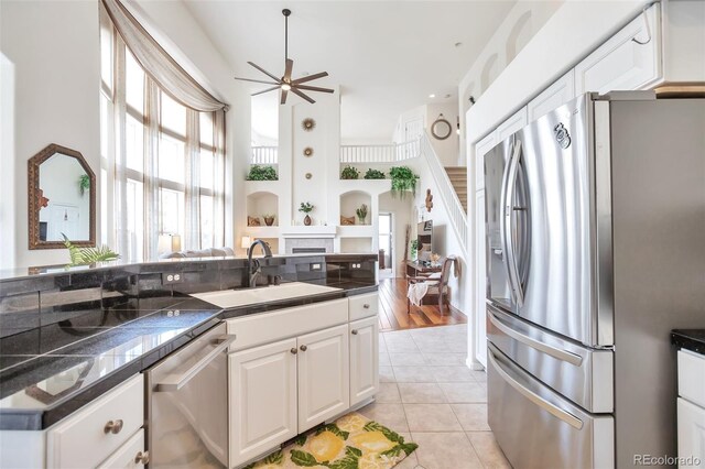 9371 Desert Willow Trl, Highlands Ranch, CO 80129 - kitchen featuring stainless steel appliances, a sink, ceiling fan, a fireplace, and white cabinetry