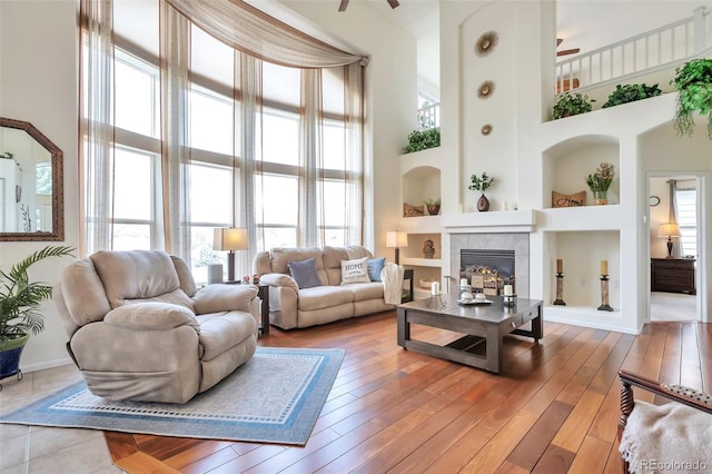 9371 Desert Willow Trl, Highlands Ranch, CO 80129 - living room featuring a towering ceiling, ceiling fan, healthy amount of natural light, built in features, and a fireplace