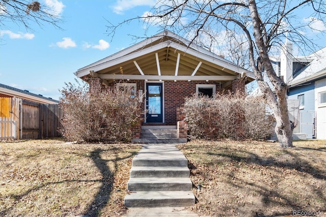 view of front of home with brick siding and fence