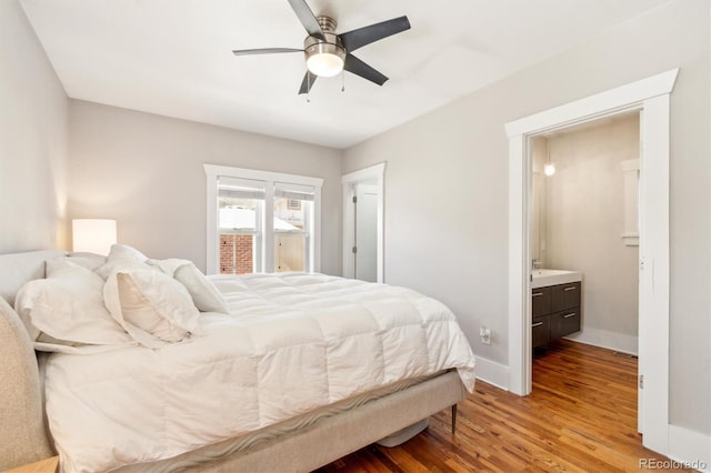 bedroom featuring a ceiling fan, baseboards, wood finished floors, and ensuite bathroom