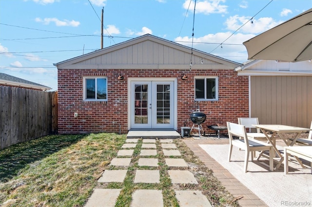 rear view of house featuring a patio, fence, french doors, and brick siding