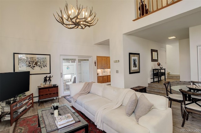 living room featuring a chandelier, stairway, a baseboard radiator, and wood finished floors