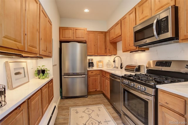 kitchen featuring a toaster, recessed lighting, a sink, appliances with stainless steel finishes, and light wood finished floors