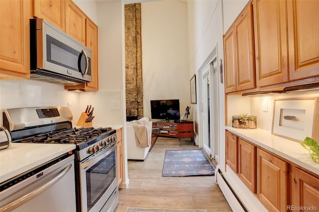 kitchen with stainless steel appliances, light wood-type flooring, open floor plan, and light countertops