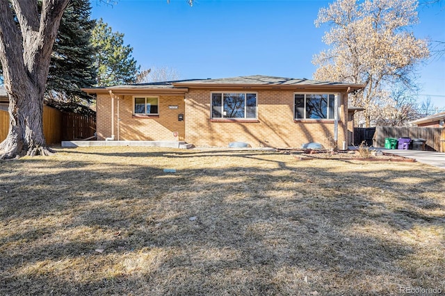 rear view of house featuring a yard, brick siding, and fence