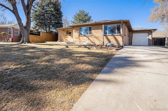 view of front of house featuring an attached garage, fence, concrete driveway, and brick siding