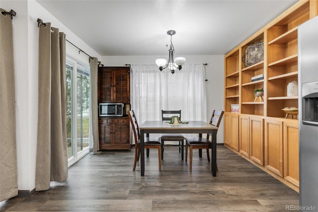 dining area with dark wood-type flooring and a notable chandelier