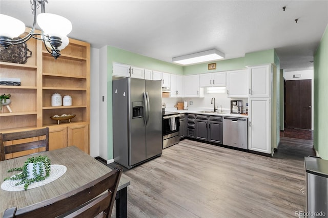 kitchen featuring pendant lighting, sink, light wood-type flooring, appliances with stainless steel finishes, and white cabinetry