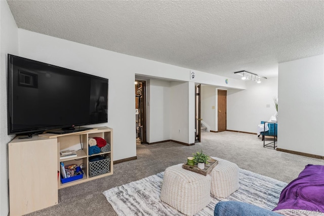 living room featuring carpet flooring, track lighting, and a textured ceiling