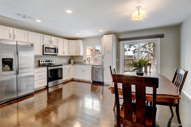 kitchen featuring light stone countertops, white cabinets, appliances with stainless steel finishes, and sink