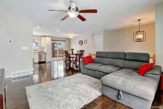 living room featuring ceiling fan with notable chandelier and dark hardwood / wood-style flooring