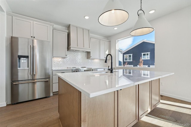 kitchen with stainless steel appliances, white cabinetry, a kitchen island with sink, and sink