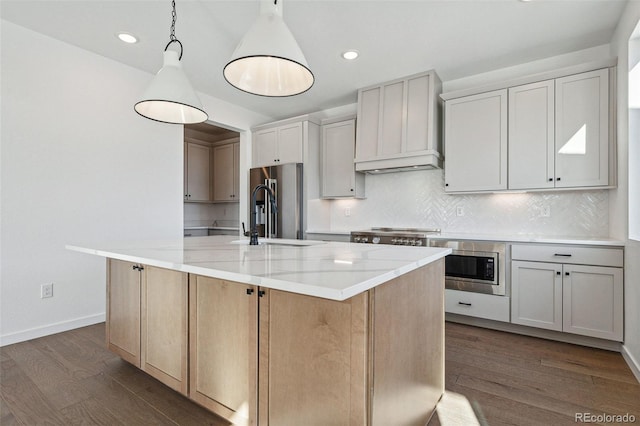 kitchen featuring custom exhaust hood, a large island with sink, hanging light fixtures, light stone countertops, and dark hardwood / wood-style flooring