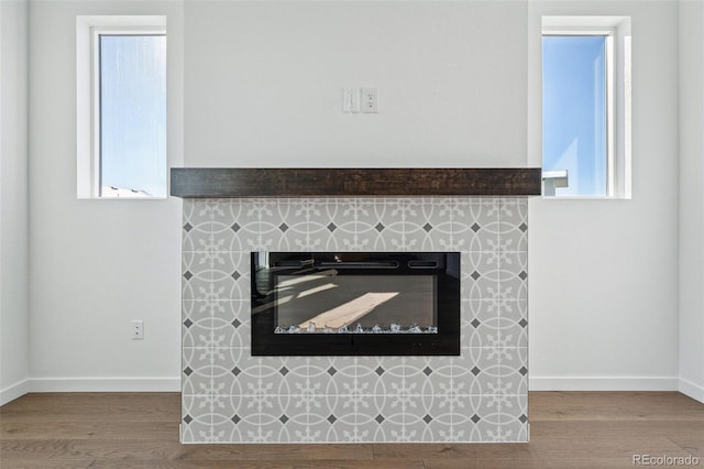 interior details with hardwood / wood-style flooring and a tiled fireplace