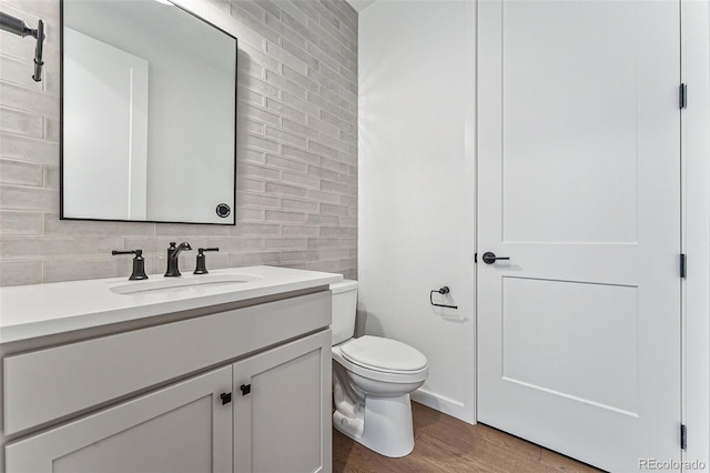 bathroom featuring decorative backsplash, toilet, vanity, and hardwood / wood-style flooring