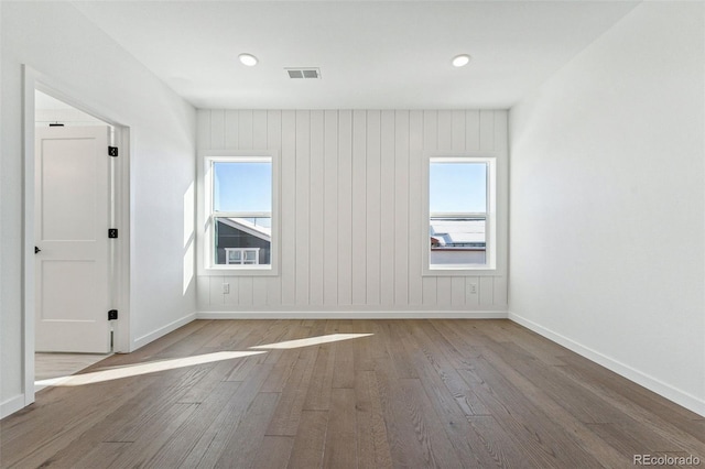 empty room with hardwood / wood-style flooring and wood walls