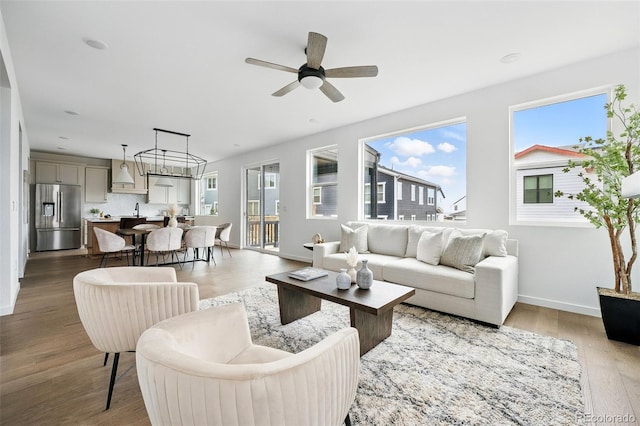 living area with wood finished floors, baseboards, a wealth of natural light, and ceiling fan