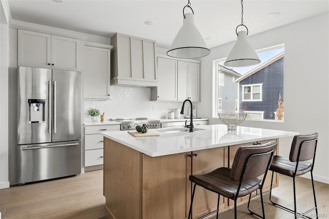 kitchen with stainless steel fridge with ice dispenser, a sink, stove, light countertops, and light wood-type flooring