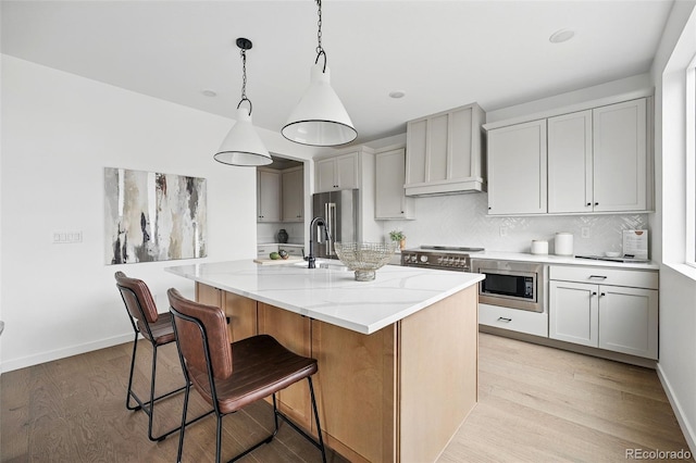 kitchen featuring custom range hood, light stone countertops, light wood-style flooring, and appliances with stainless steel finishes