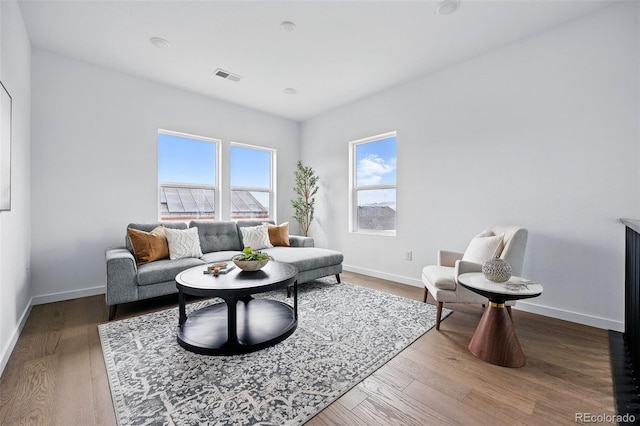 living area with visible vents, baseboards, and wood finished floors