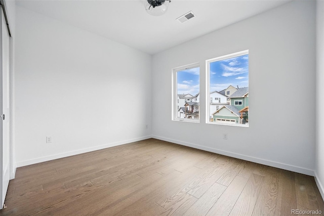 spare room featuring visible vents, wood finished floors, and baseboards