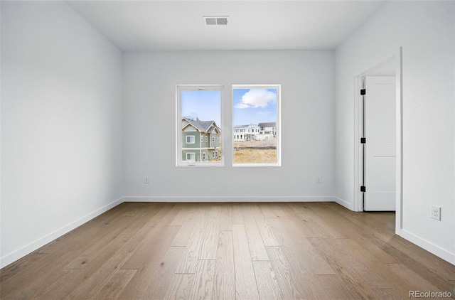 empty room featuring visible vents, baseboards, and wood finished floors