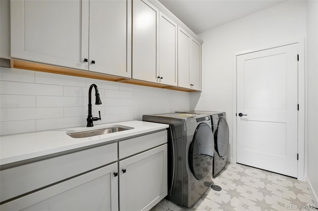 washroom featuring washing machine and dryer, cabinet space, light floors, and a sink