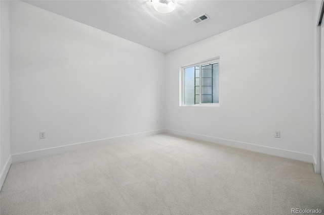 spare room featuring visible vents, light colored carpet, and baseboards