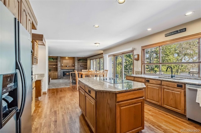 2154 S Parfet Dr, Lakewood, CO 80227 - kitchen featuring stainless steel appliances, a sink, light stone counters, a center island, and brown cabinets