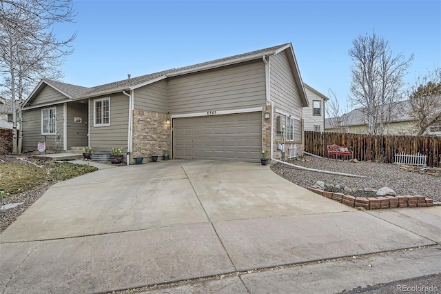 view of front of home featuring a garage, brick siding, concrete driveway, and fence