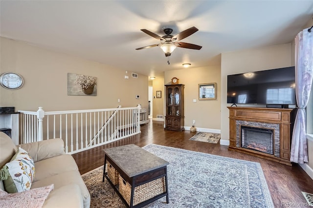 living room with a fireplace, wood finished floors, visible vents, and baseboards