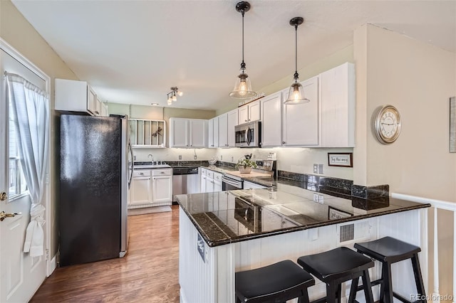 kitchen with a peninsula, a breakfast bar area, wood finished floors, and appliances with stainless steel finishes