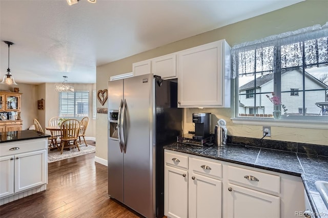 kitchen with decorative light fixtures, dark wood finished floors, stainless steel fridge, white cabinets, and baseboards