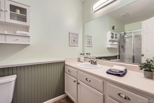 full bathroom featuring visible vents, a shower stall, a wainscoted wall, toilet, and vanity