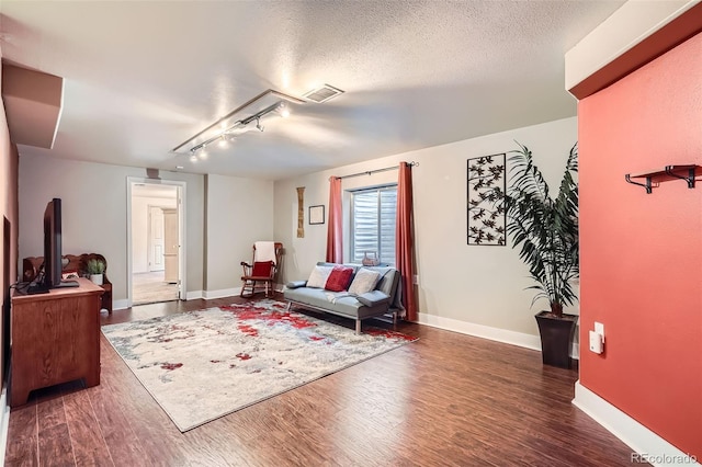 living area featuring baseboards, wood finished floors, visible vents, and a textured ceiling