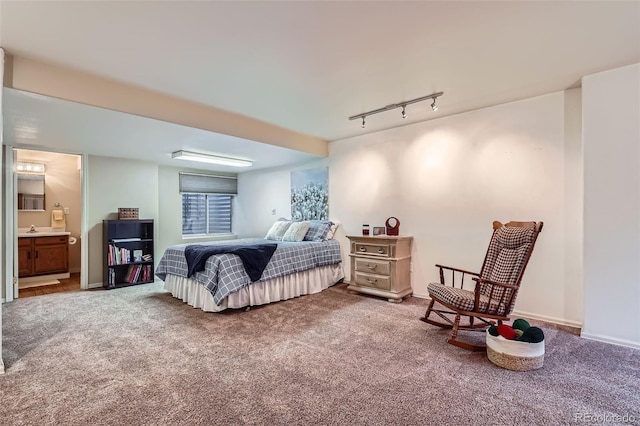 carpeted bedroom featuring connected bathroom, baseboards, and track lighting