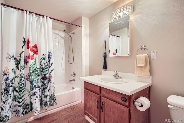 bathroom featuring visible vents, toilet, wood finished floors, shower / tub combo, and vanity