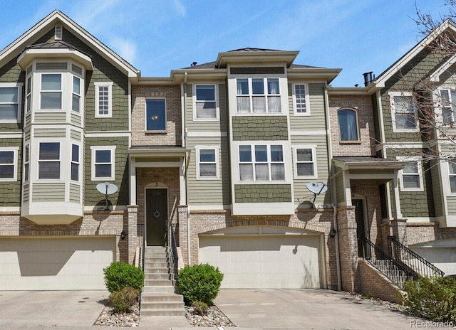 townhome / multi-family property with a garage, driveway, and brick siding