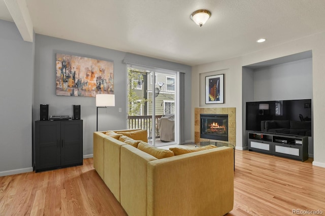 living room featuring light wood-style floors, a fireplace, and baseboards