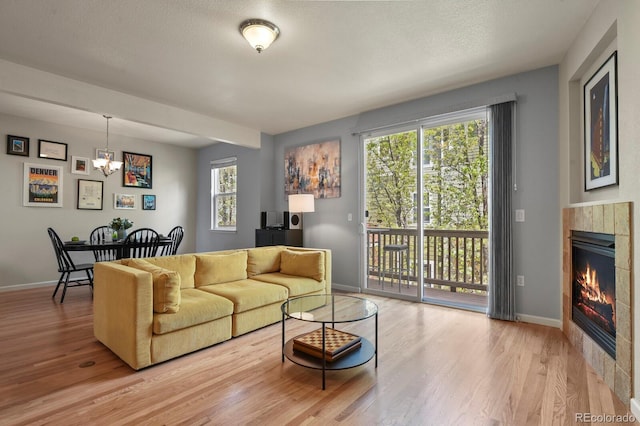 living room featuring wood finished floors, baseboards, a chandelier, and a fireplace