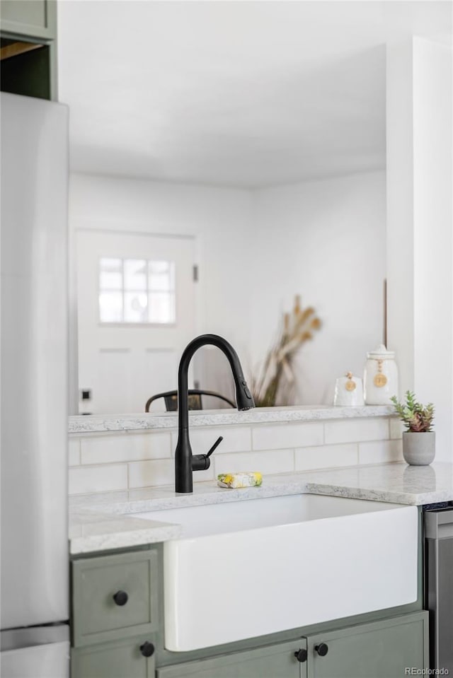 room details with light stone countertops, sink, stainless steel fridge, and green cabinetry